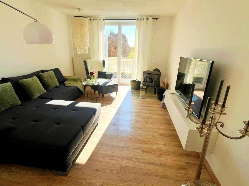 a living room with a black couch and a tv at Hochsitz Appartement in Seelitz