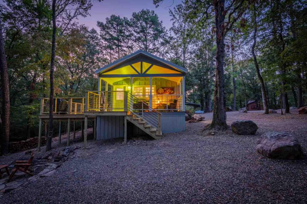 a small house in the middle of a forest at Hot Tub Firepit Dreams Streamside Hochatown in Broken Bow