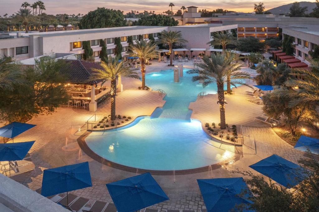 an overhead view of a pool with palm trees and blue umbrellas at The Scottsdale Resort & Spa, Curio Collection by Hilton in Scottsdale