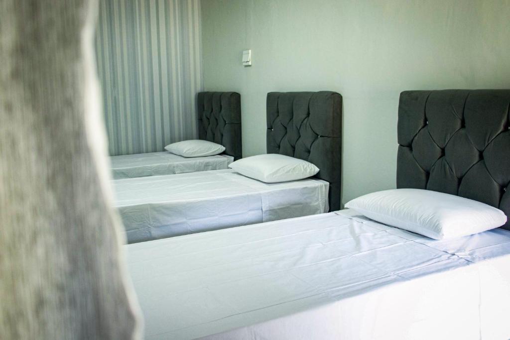 two beds in a room with white sheets at Pousada da Isa in Quatro Barras