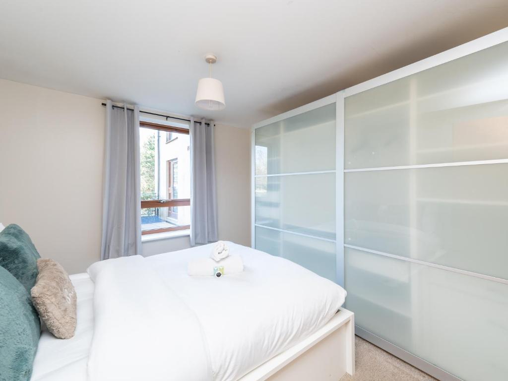 a bedroom with a white bed and a glass wall at Crawley 2 bed flat with Parking in Crawley