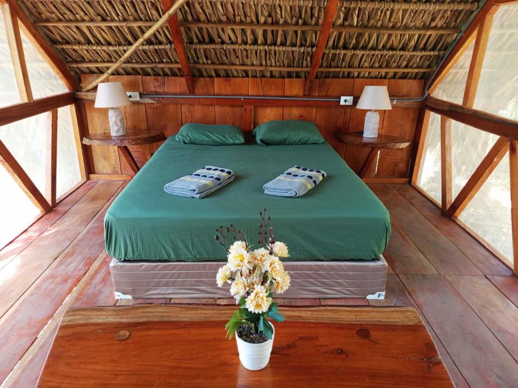 a bed in a wooden room with a vase of flowers at Cielo y Tierra in Santa Cruz