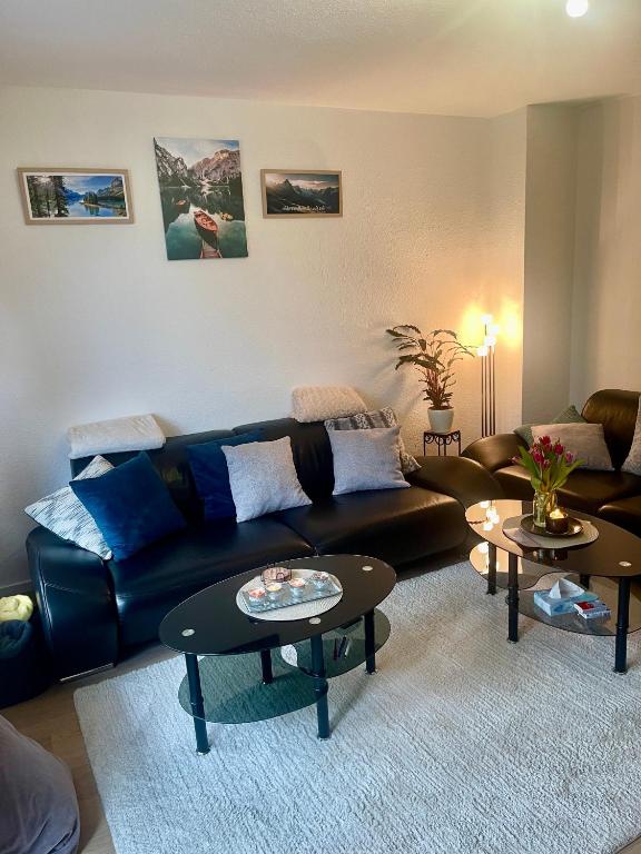 a living room with a black leather couch and two tables at Ferienwohnung Emma in Castrop-Rauxel