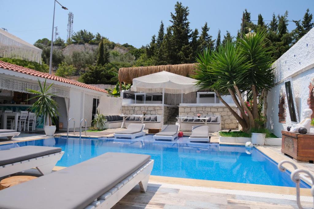 a swimming pool with lounge chairs and a house at Alacati Naz Konak in Çeşme
