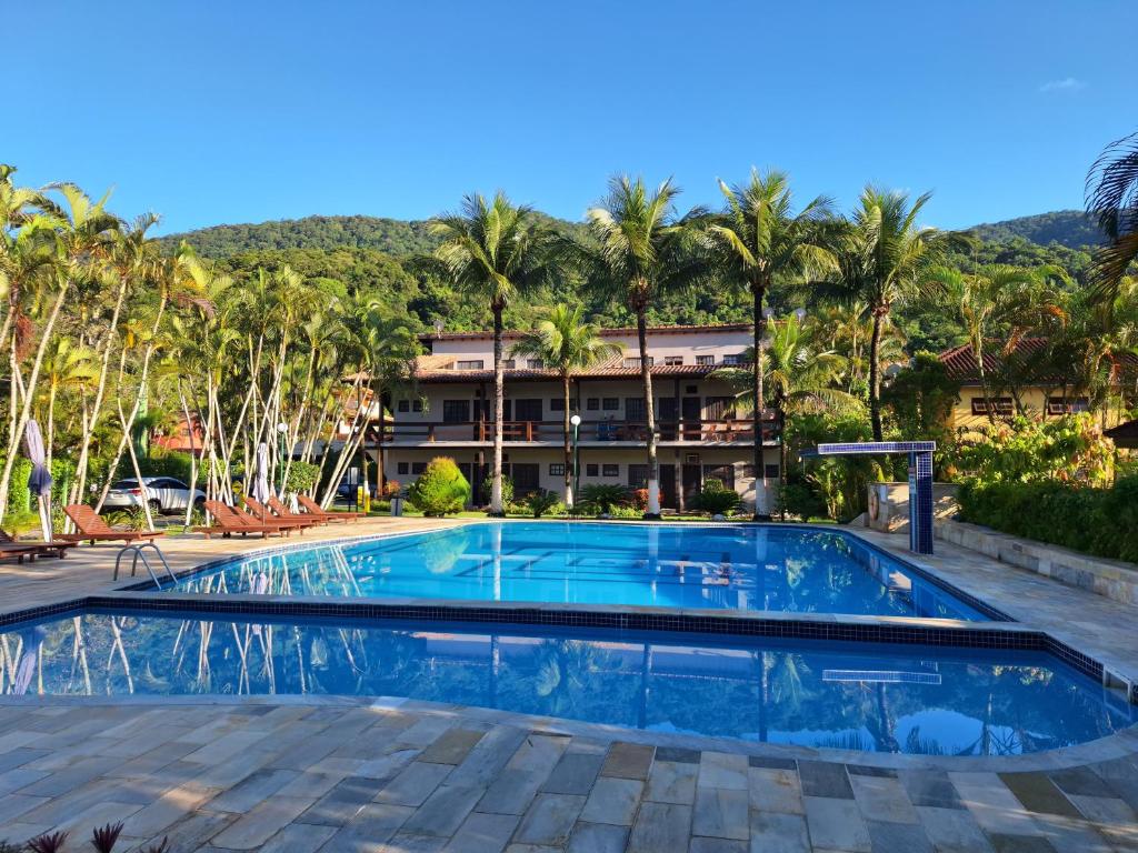 a pool in front of a resort with palm trees at Apartamento em Maresias a 100 metros da praia in Maresias