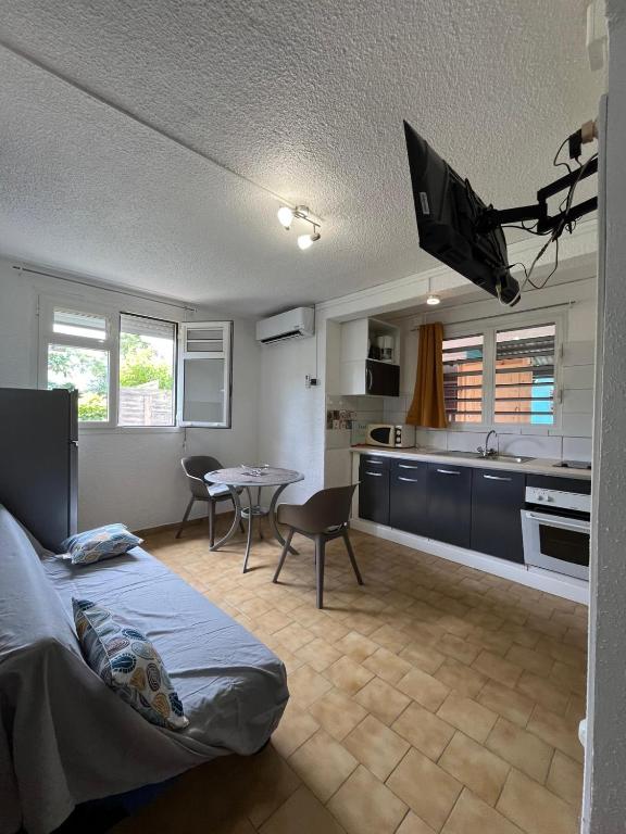 a bedroom with a bed and a kitchen with a table at Les 2 Cocotiers - Studios in Sainte-Luce