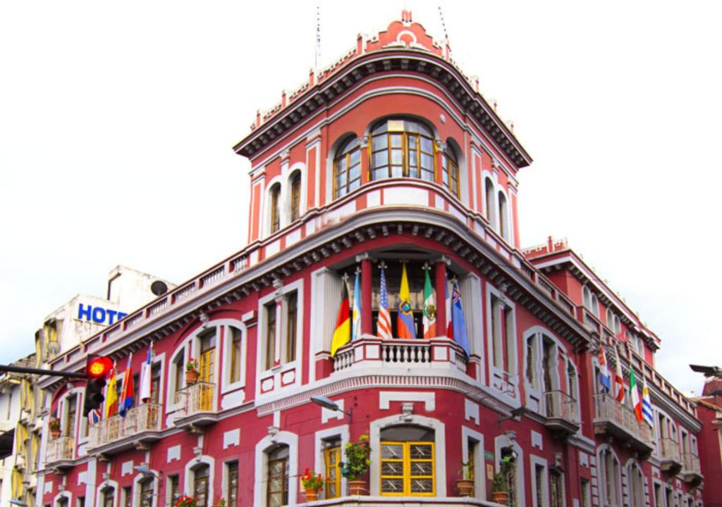 a red building with flags on top of it at Hotel Plaza del Teatro in Quito
