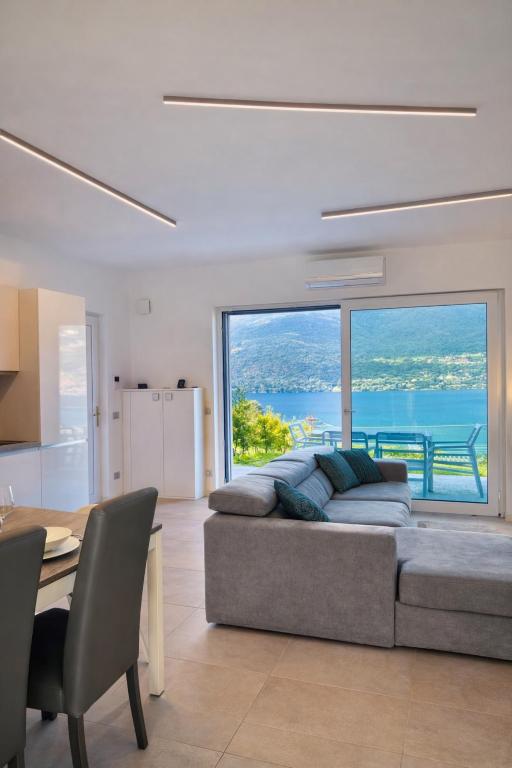 a living room with a couch and a large window at Bluelow Lakeview house in Dervio