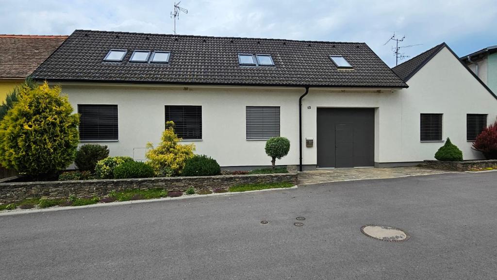 a white house with a black roof and a driveway at Ve dvoře in Výrovice