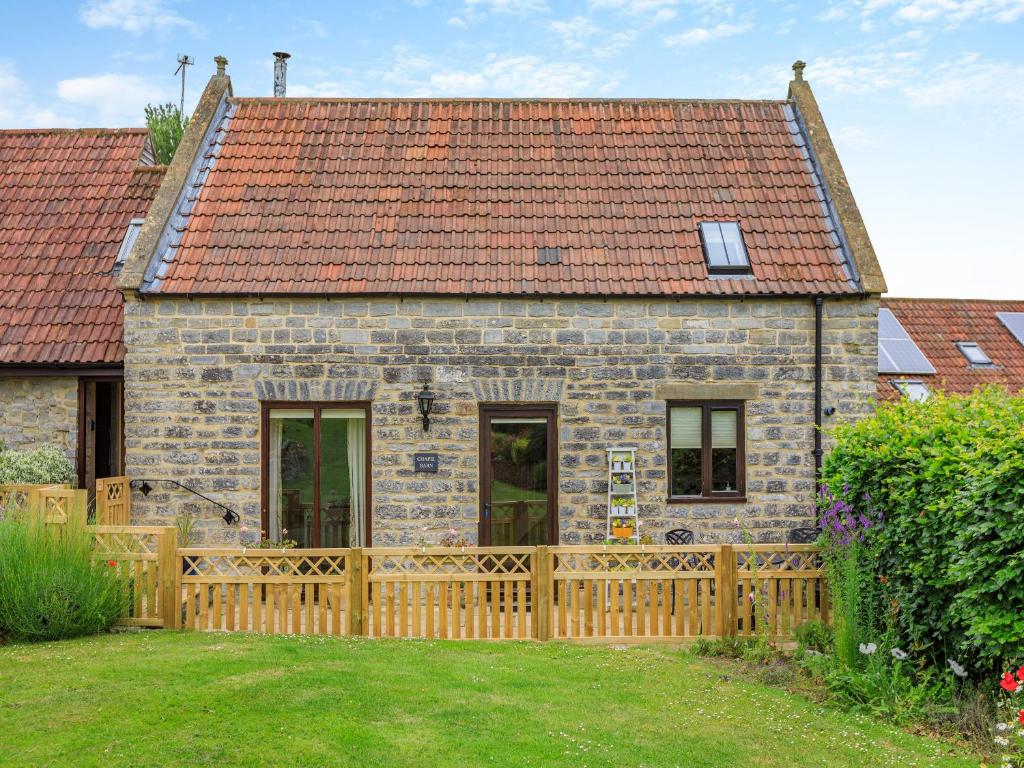 a house with a wooden fence in front of it at Chapel Barn - Uk46738 in Shapwick