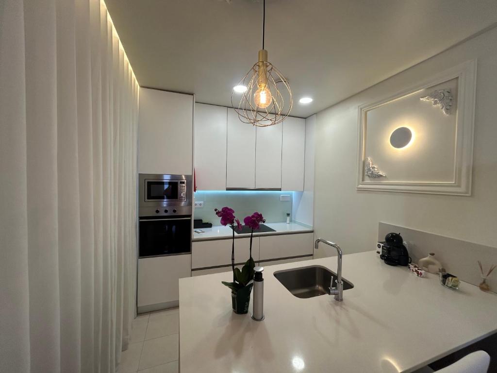 a kitchen with a sink and a counter with flowers on it at Boavista Apartments in Paredes de Coura