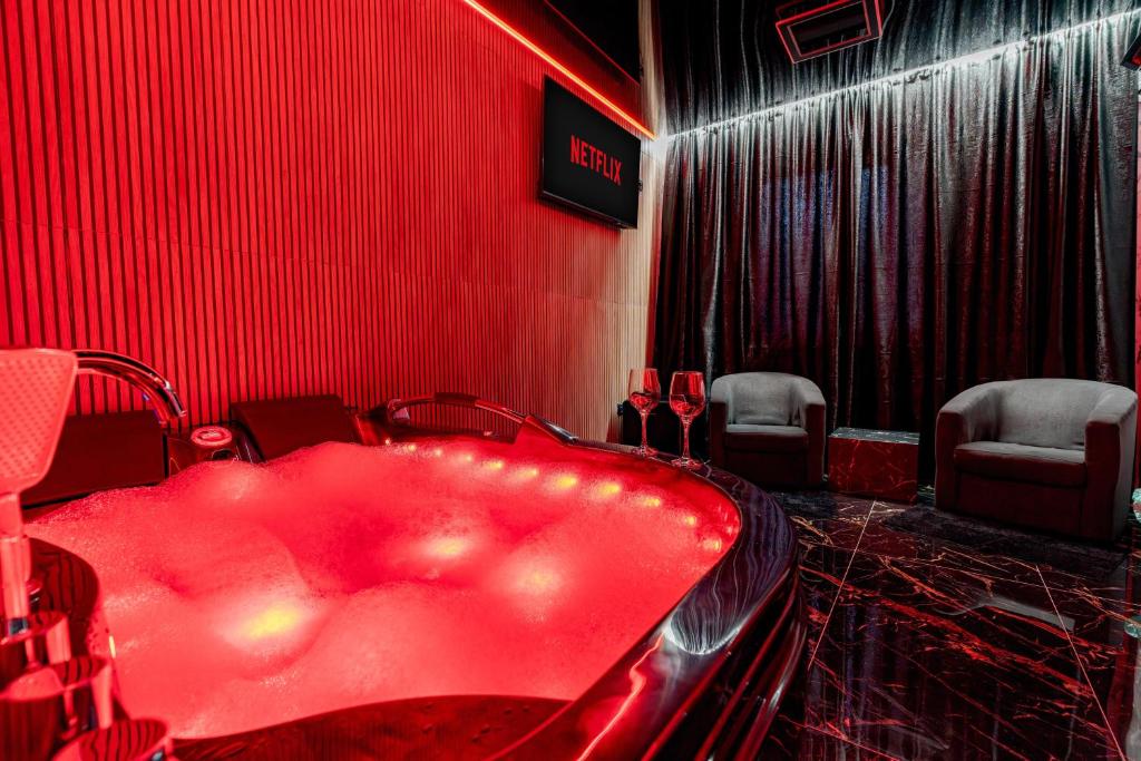 a red bath tub in a red room with chairs at Love & Jacuzzi in Bucharest