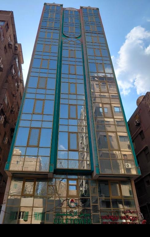 a tall glass building with a reflection of a building at Gulf Suites Cairo in Cairo