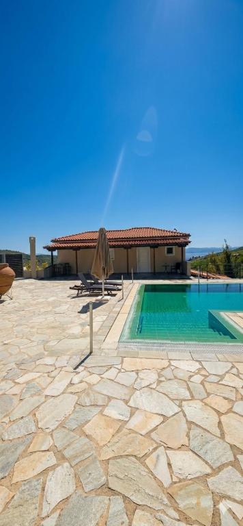 a pool with a chair and a umbrella and a building at Villa Anemoessa in Kolios