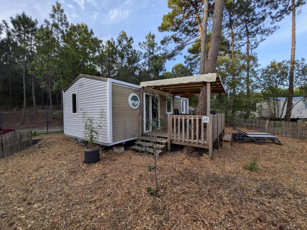 a white tiny house with a porch and a tree at Bungalow mahi-mahi in Lacanau
