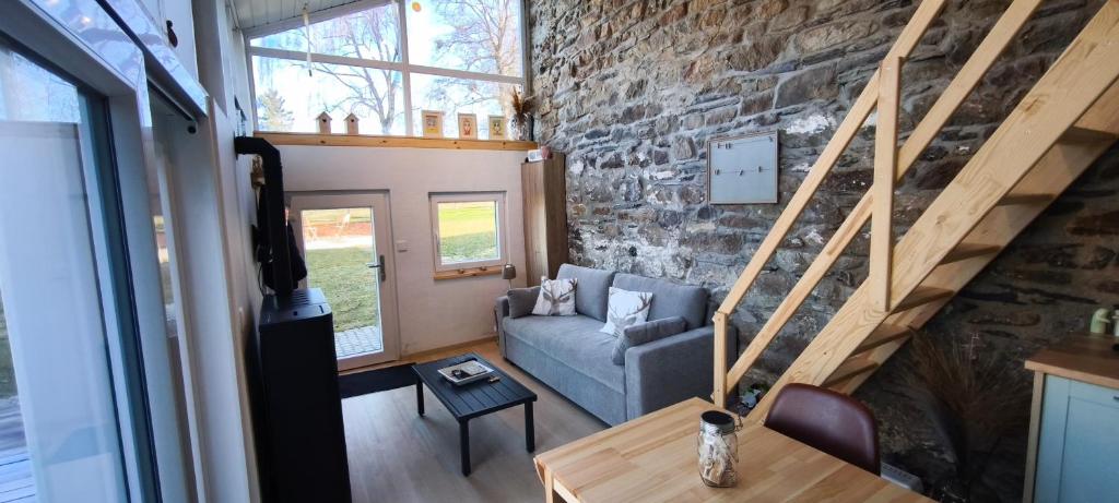 a living room with a couch and a stone wall at En aparté in Vielsalm
