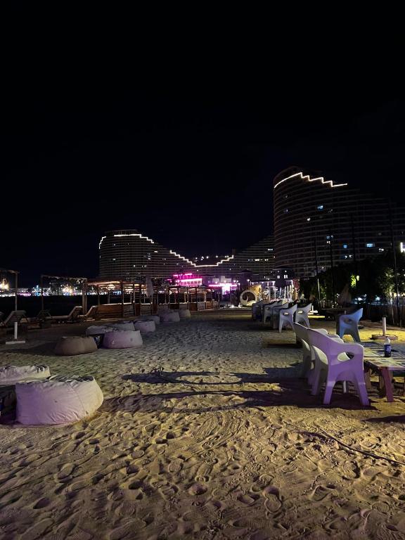 a sandy beach at night with chairs and buildings at Prime Plaza Porto Towers Stay Hotel VIP in Ain Sokhna