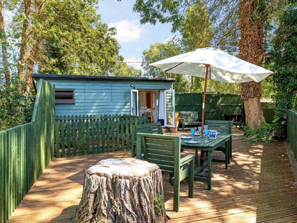 Ein Tisch mit Sonnenschirm neben einem Schuppen in der Unterkunft Island Lodge - Uk46767 in Little Baddow
