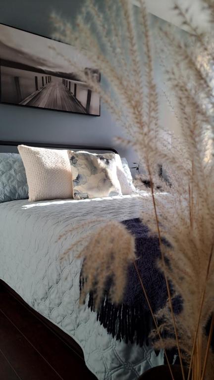 a bedroom with a bed with white sheets and a plant at Shediac Beach Suite- Pointe du Chene Wharf and Parlee Beach in Pointe-du-Chêne