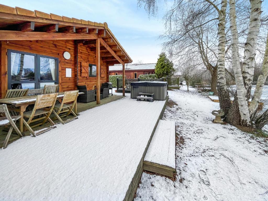a wooden cabin with a bench in the snow at Avocet Lodge in Horncastle