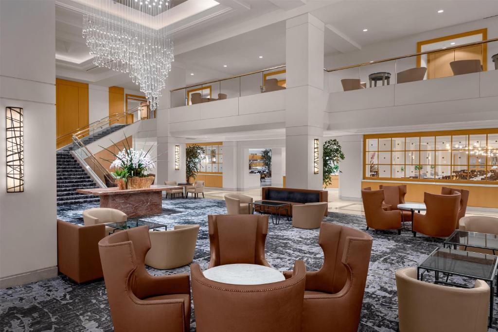 a lobby with chairs and tables and a staircase at Hilton Los Angeles Airport in Los Angeles