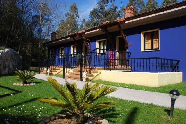 una casa azul con una palmera delante de ella en Apartamentos Rurales Les Mestes, en Tazones