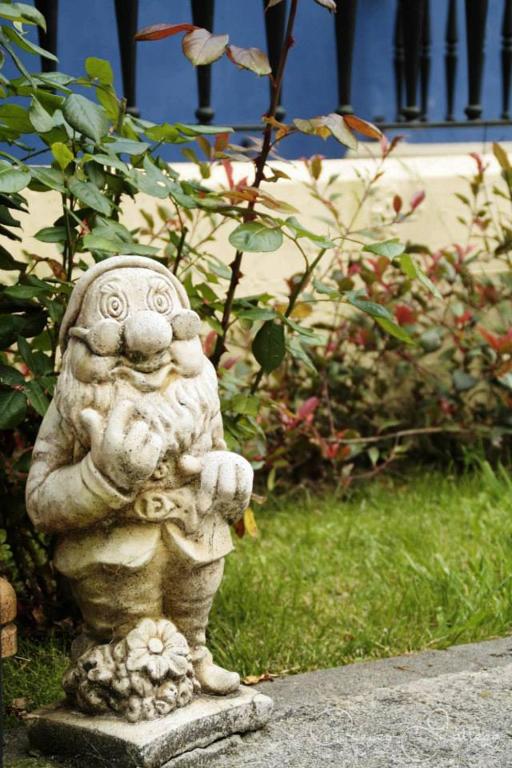 a stone statue sitting on the ground in a garden at Apartamentos Rurales Les Mestes in Tazones