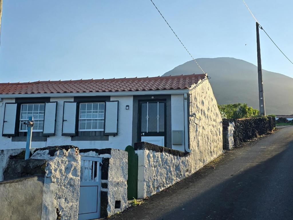 a white house with a stone wall next to a street at Vista Pico House in Madalena
