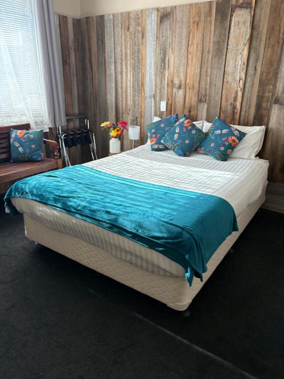 a bedroom with a large bed with blue pillows at The Bears in Geeveston