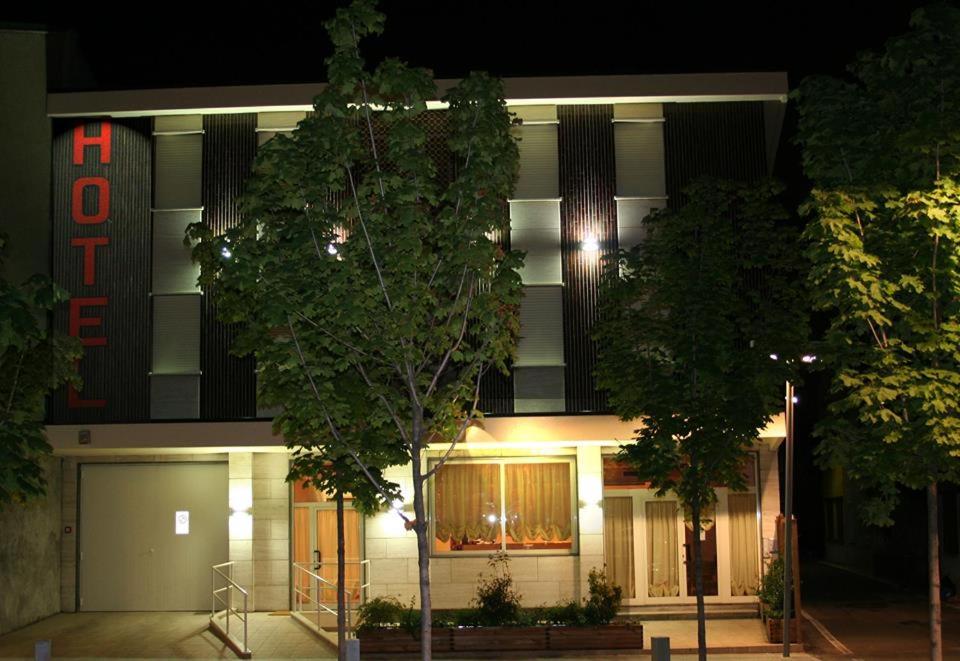 um edifício iluminado com uma árvore em frente em Albergo Munsci' em Rovello Porro