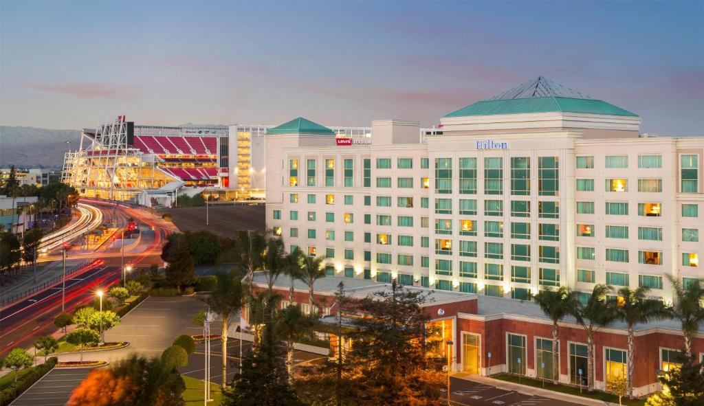 a large white building with a green roof on a city street at Hilton Santa Clara - Newly Renovated in Santa Clara