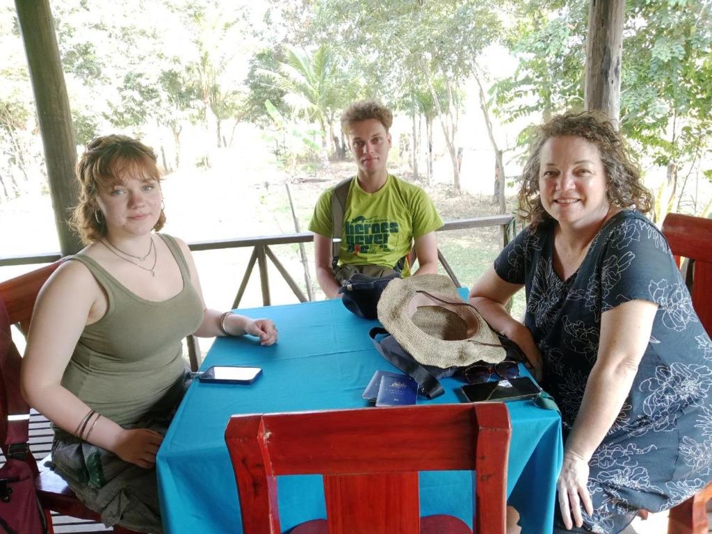 two women and a man sitting at a blue table at Chanmolfarmstay in Phumĭ Chŭb Chănt Sâr