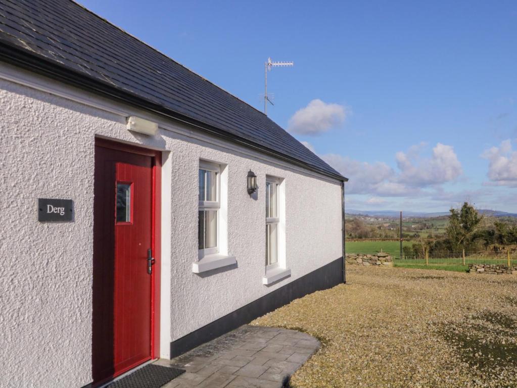 a small white building with a red door at Derg Cottage in Strabane