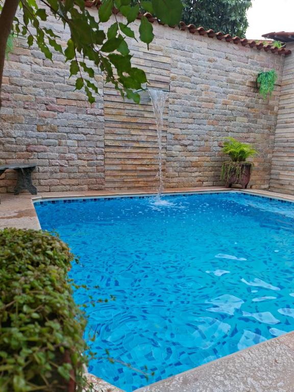 a swimming pool with a waterfall in a brick wall at Cantinho Abençoado in Pirenópolis