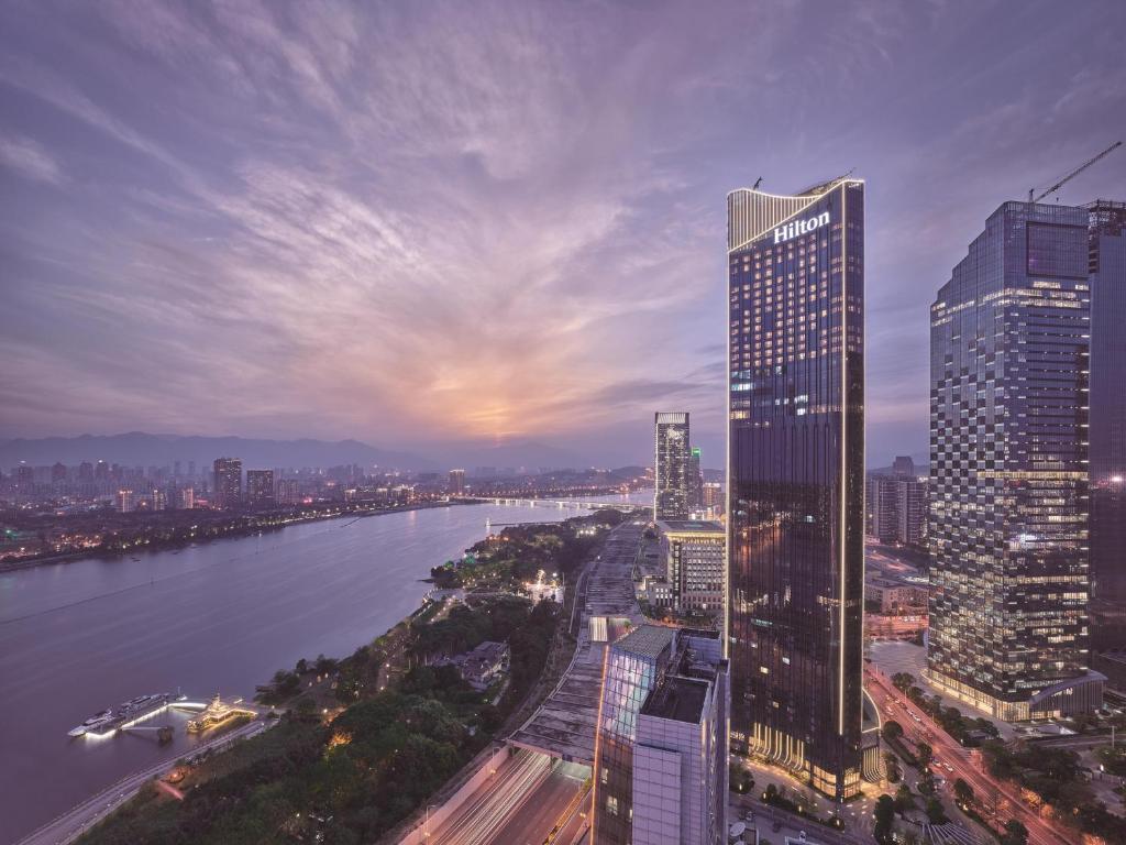 a city skyline with a tall building and a river at Hilton Fuzhou in Fuzhou