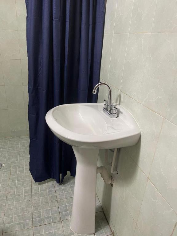 a white sink in a bathroom with a blue shower curtain at Sandy's in Morelia