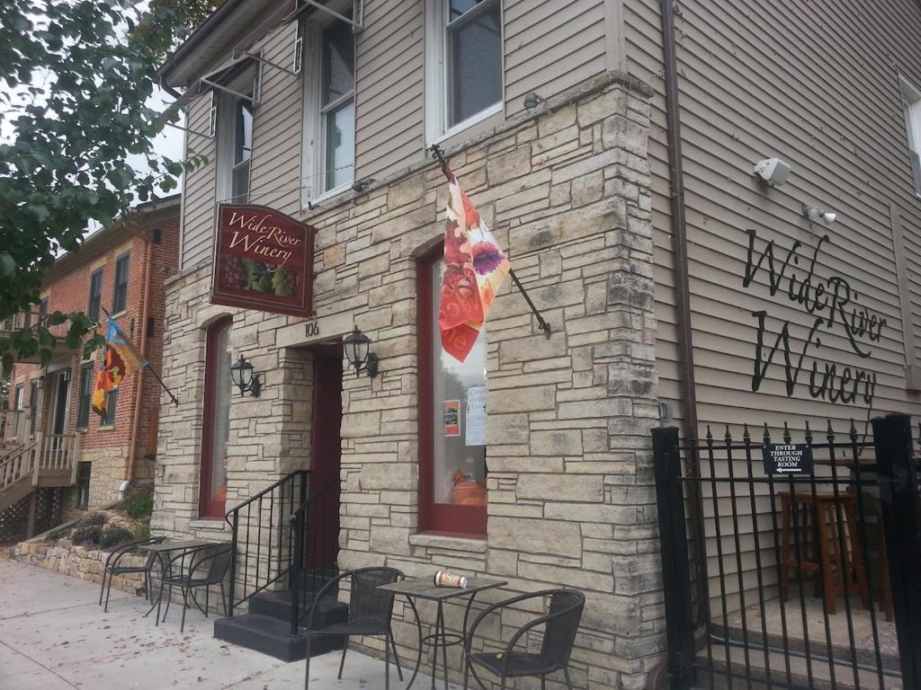 a brick building with tables and chairs outside of it at Wide River Winery Inn in Le Claire