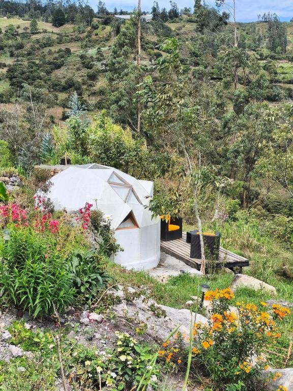a white building on a hill with flowers at Casa Camprestre Hika in Machetá