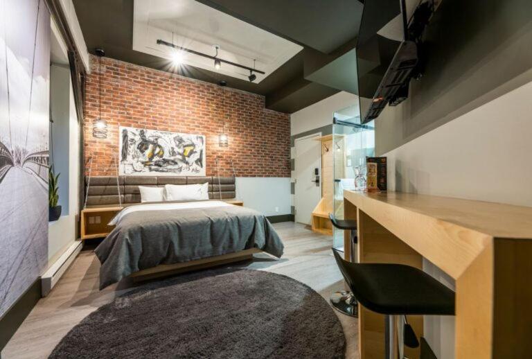 a bedroom with a bed and a brick wall at La Suite Hotel in Shawinigan
