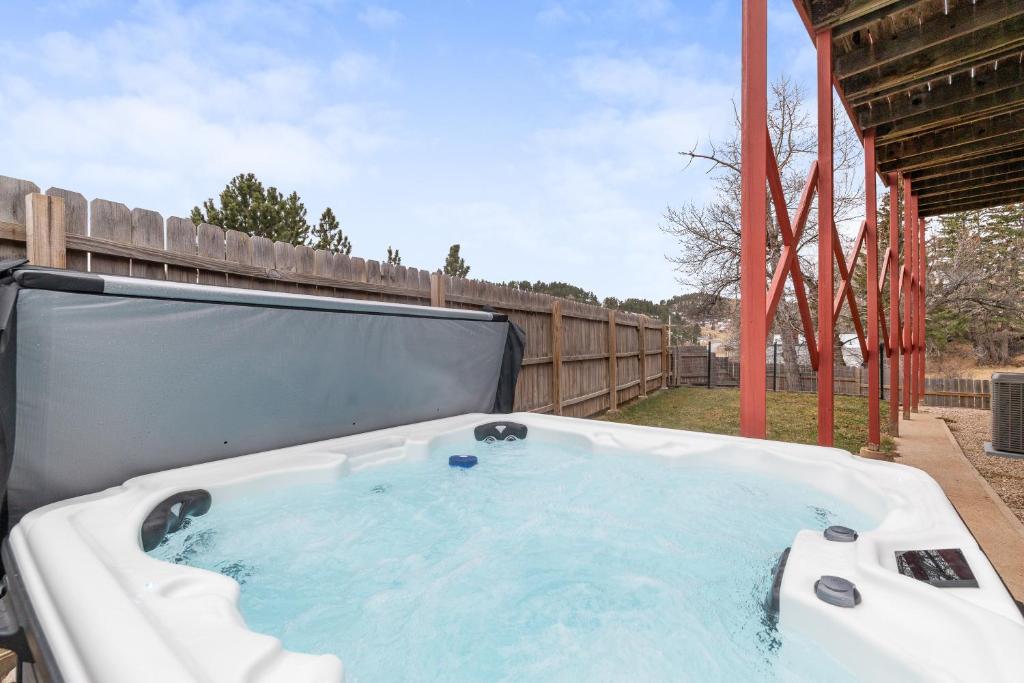 ein Whirlpool in einem Garten mit Zaun in der Unterkunft Lead Haven Lodge in Lead