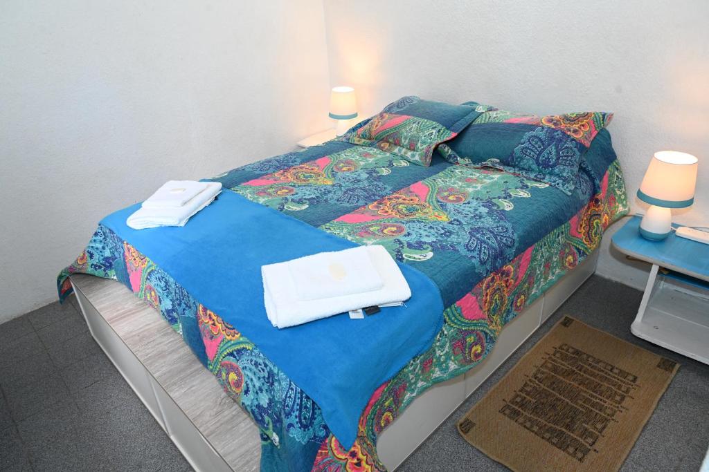 a bed with a blue comforter and towels on it at Como en casa in Rawson
