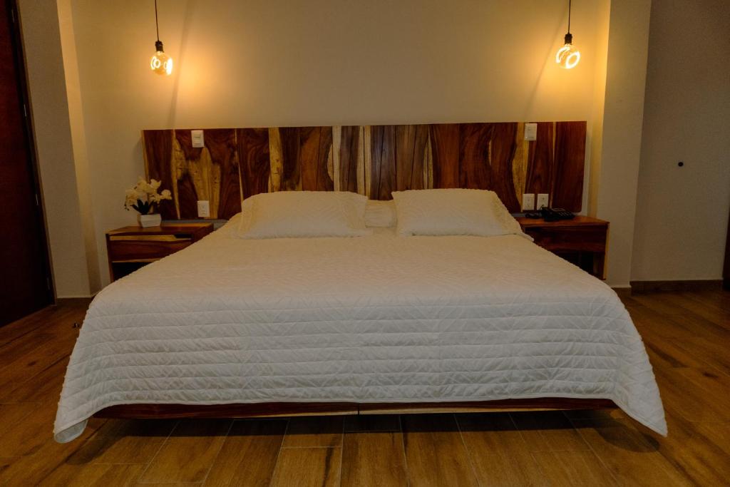 a bedroom with a large bed with a wooden headboard at Hotel Tres Reinas in Xicotepec de Juárez