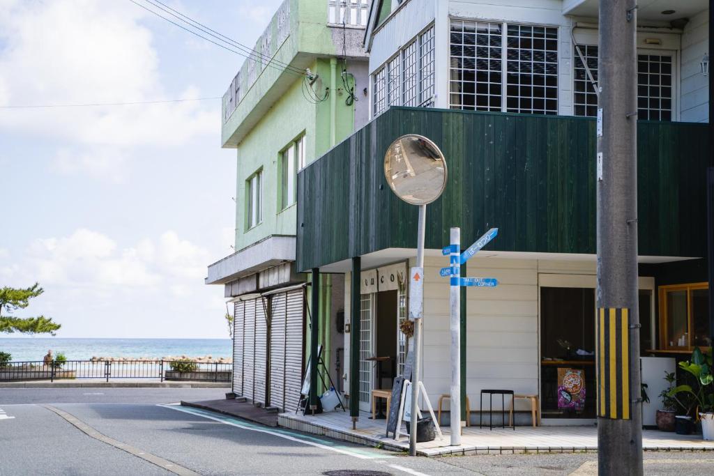 a building on a street with the ocean in the background at Coucou House Gra in Toyooka