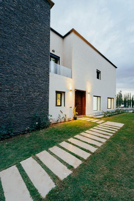 a large white house with a brick wall at Atlas Serenity Villa Marrakech in Sbiti
