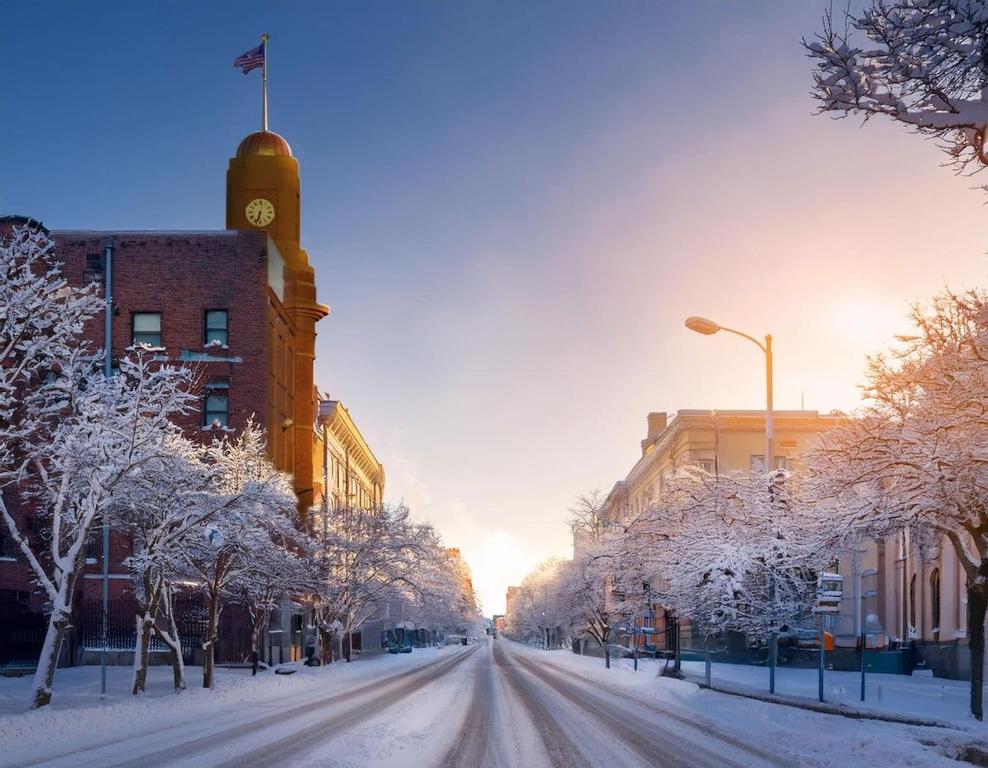 a snowy street in a city with a clock tower at SkyBox|Rooftop|Downtown in Traverse City