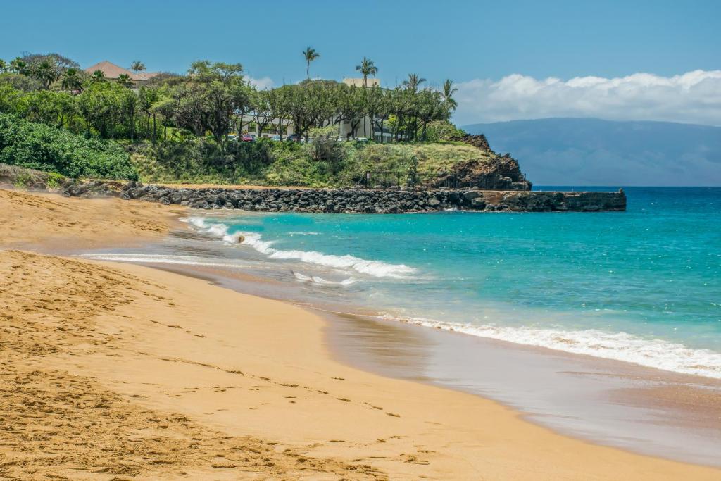 a sandy beach with the ocean and palm trees at Kaanapali Maui at the Eldorado by OUTRIGGER - Select Your Unit in Lahaina