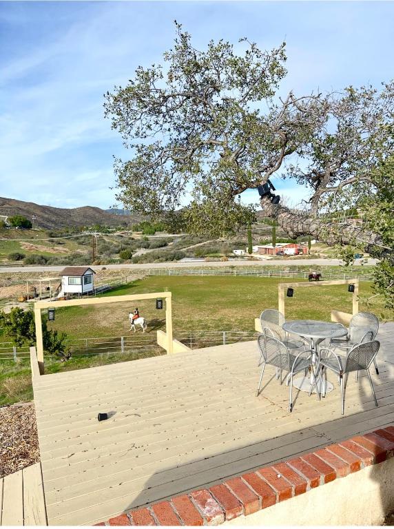 a patio with a table and chairs and a field at Zaromelranch deck in Agua Dulce