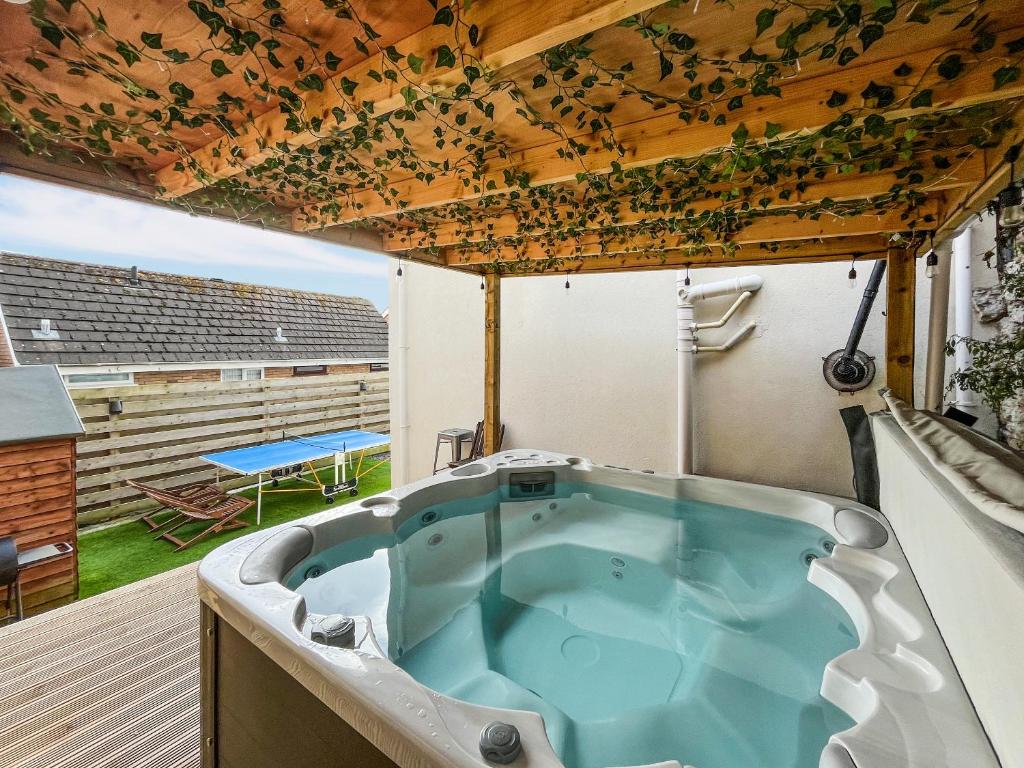 a jacuzzi tub on a deck with a table at Sea-Scape in Penrhyn Bay