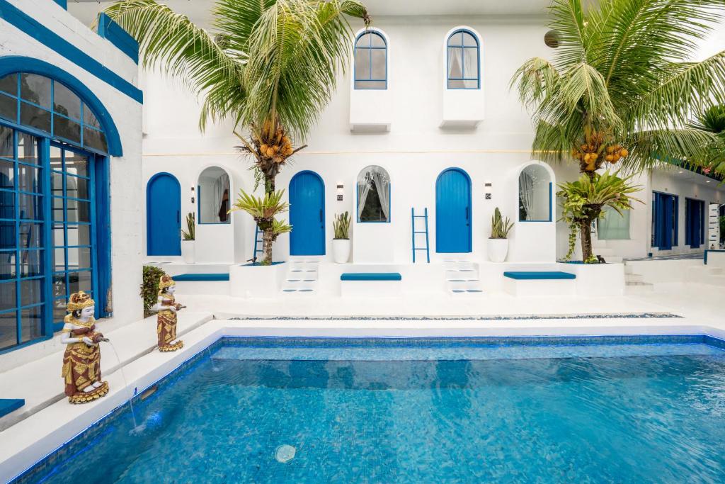 a villa with a swimming pool and palm trees at Bombora Surf Camp in Uluwatu