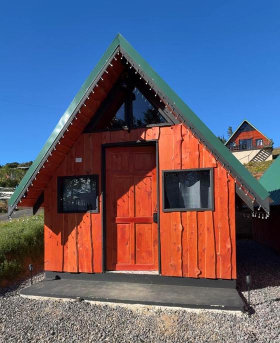 a red shed with a door and two windows at Cabaña Joy-C Colibri 1 in El Copey